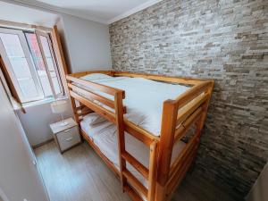 a bedroom with two bunk beds and a brick wall at Aliciamar 29 by Casas de Setúbal in Setúbal