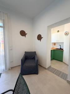 a living room with a chair and a kitchen at Paloma in Santa Flavia