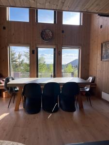 a table and chairs in a room with windows at Moderne hytte ved sjøen med badstue in Rømskog