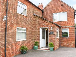 a red brick house with a white door at The Cottage, Poplars Farm in Ashbourne