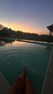 a person laying in a pool of water at sunset at Cabaña en cañuelas in Cañuelas