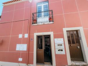 a pink building with a door and a balcony at Aliciamar 29 by Casas de Setúbal in Setúbal