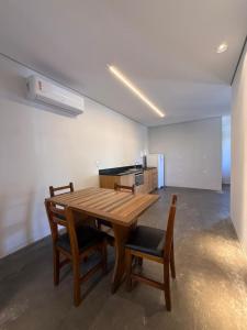 a wooden table and chairs in a room with a kitchen at Pitaya Apart Hotel in Garopaba