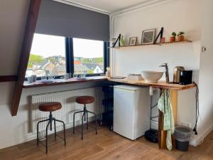 a kitchen with two stools and a counter with a window at Room at the Beach Egmond in Egmond aan Zee