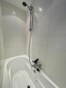 a white bath tub with a shower in a bathroom at Room at the Beach Egmond in Egmond aan Zee +15 photos