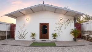a white house with a brown door and plants at Gardens by Lotels in Madambakkam