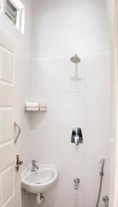 a white bathroom with a sink and a shower at Gardens by Lotels in Madambakkam