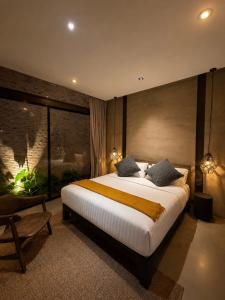 a bedroom with a large bed and a large window at Makham Villa River Kwai in Kanchanaburi City