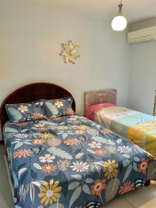 a bedroom with a bed with a blue floral comforter at Chalé no coração de Penedo - Pet Friendly in Itatiaia +20 photos