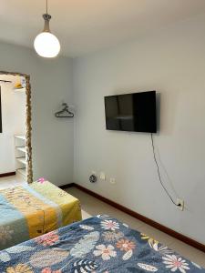 a bedroom with two beds and a flat screen tv on the wall at Chalé no coração de Penedo - Pet Friendly in Itatiaia