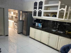 a kitchen with white cabinets and a stainless steel refrigerator at Villa le Dakota la différence in Yaoundé