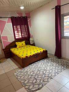 a bedroom with a bed with yellow sheets and a rug at Villa le Dakota la différence in Yaoundé