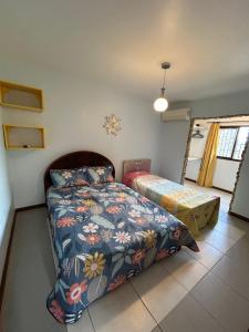 a bedroom with a bed and a bedspread with flowers at Chalé no coração de Penedo - Pet Friendly in Itatiaia