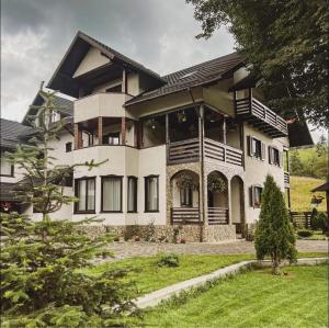 a large white house with a yard at Casa Corlățeni in Pojorâta