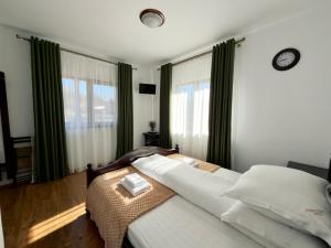 a bedroom with a bed and two windows with green curtains at Casa Corlățeni in Pojorâta