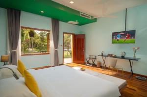 a bedroom with a large white bed and a television at Habana Angkor Resort in Siem Reap