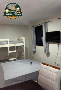 a bedroom with two bunk beds and a flat screen tv at Hospedagem e pizzaria florestinha in Búzios