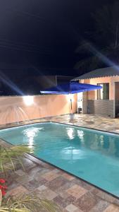 a swimming pool at night with a blue umbrella at Hospedagem e pizzaria florestinha in Búzios
