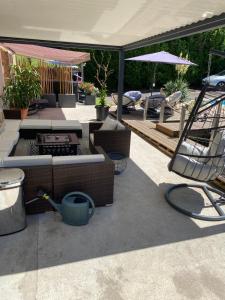 a patio with tables and chairs and an umbrella at Les chambres dhotes de la croix bleue 2 in Murinais