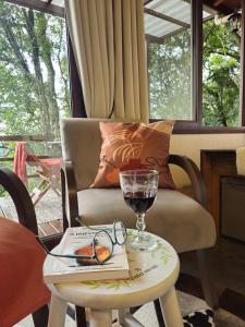 a glass of wine on a table next to a chair at Recanto Vista Verde in Nova Petrópolis