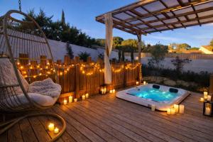a deck with a hot tub and candles and a chair at Les Gîtes de Laure - L'Eden Romantique, B&B, Spa privatif et Petit Déjeuner, Couloir de nage, 10mn Carcassonne in Malves