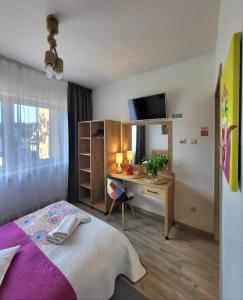 a bedroom with a bed and a desk and a television at Pokoje Gościnne U Anny in Nowy Targ