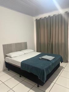 a bedroom with a bed with a blue blanket on it at Flat a 3 minutos do centro de Chapecó in Chapecó