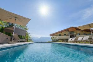 a swimming pool with chairs and umbrellas next to a building at Apfelhof in Termeno