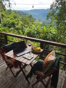 a table with a laptop and a bowl of fruit on a balcony at Recanto Vista Verde in Nova Petrópolis