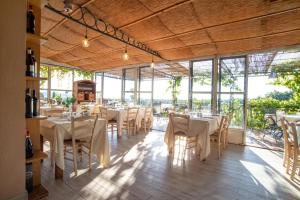a restaurant with white tables and chairs and windows at Agriturismo Cerrosughero in Canino