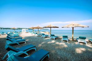 a group of chairs and umbrellas on a beach at Maja Apartment 3 in Funtana