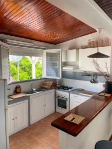 a kitchen with white cabinets and a wooden ceiling at Pépite Anses in Les Anses-dʼArlets