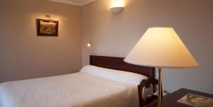 a bedroom with a bed and a lamp on a table at Hôtel des Pyrénées in Saint-Jean-Pied-de-Port