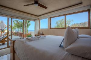 ein weißes Bett in einem Zimmer mit großen Fenstern in der Unterkunft Xeno Hotel Boutique in Playa Estacahuite + 126 Fotos