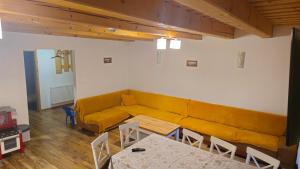 a living room with a yellow couch and tables at Chalupa Chotár in Terchová +12 photos