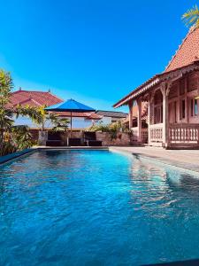 a swimming pool in front of a house at Joglo Ulu Home in Uluwatu