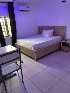 a room with a bed and a chair in it at Lloyd Hotel and Suites in Benin City