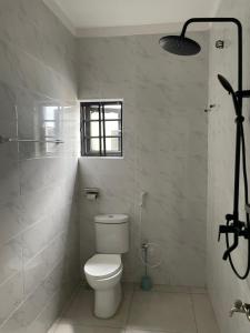 a white bathroom with a toilet and a shower at Lloyd Hotel and Suites in Benin City