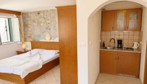 a bedroom with a bed and a kitchen at Apartments Residence Astoria in Rab