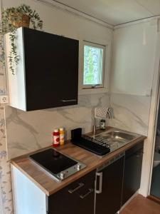 a small kitchen with a sink and a microwave at Nyrenoverad stuga mellan två sjöar in Järlåsa