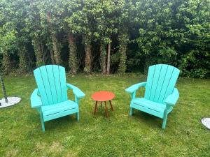 two blue chairs and a red table in the grass at Chambre Eucalyptus dans maison neuve in Bazainville