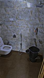 a bathroom with a toilet and a bucket at K2 Alpine Hotel in Pahalgām