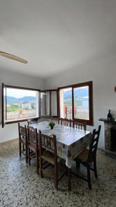 a dining room with a table and chairs and windows at La Casa de la Vall in Castellbell i Vilar