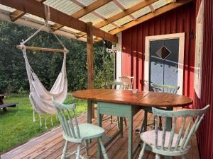 a wooden table and chairs on a deck with a hammock at Hus Blommekulla in Högsby +36 photos