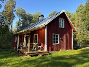 a red barn with a table and chairs on the porch at Hus Blommekulla in Högsby