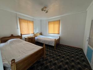 a hotel room with two beds and two windows at Sharsharai Haftkul in Panjakent