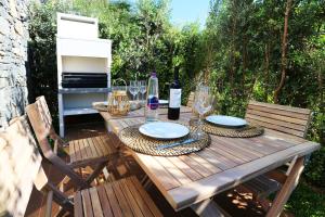 a wooden table with plates and wine glasses on it at Piu Bella in Fajã da Ovelha