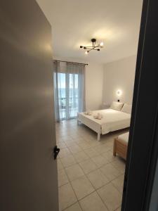 a white bedroom with a bed and a window at Oceanica k rooms in Loutsa