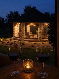 two glasses of wine sitting on a wooden table in front of a house at Pavasario Namai & SPA in Alytus +15 photos