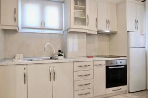 a kitchen with white cabinets and a white refrigerator at Evia Blue Aura in Khrónia +11 photos